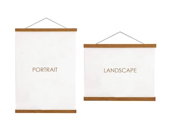 May include: Two white canvas prints with wooden magnetic poster hangers. One is vertical and labeled "PORTRAIT", the other is horizontal and labeled "LANDSCAPE". Both are suspended by a black string.