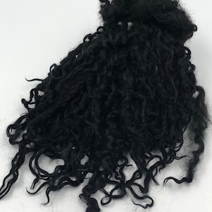 May include: A large amount of black curly wool fiber. The wool is loose and fluffy, and it appears to be hand-spun.