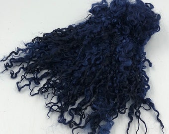 May include: A pile of dark blue and black curly wool roving. The roving is soft and fluffy, and it would be perfect for spinning or felting.