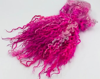 May include: A bundle of pink and white curly wool roving. The roving is a blend of wool fibers that have been carded and combed together. It is used for spinning yarn, felting, and other fiber crafts.