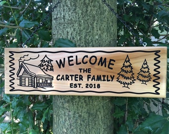 May include: Wooden welcome sign with a cabin, trees, and the text "Welcome The Carter Family Est. 2018".