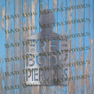May include: A metal silhouette of a person with the words "FREE BODY PIERCINGS" cut out. The silhouette is against a blue wooden background with the words "BAD DOG METALWORKS" repeated in the background.