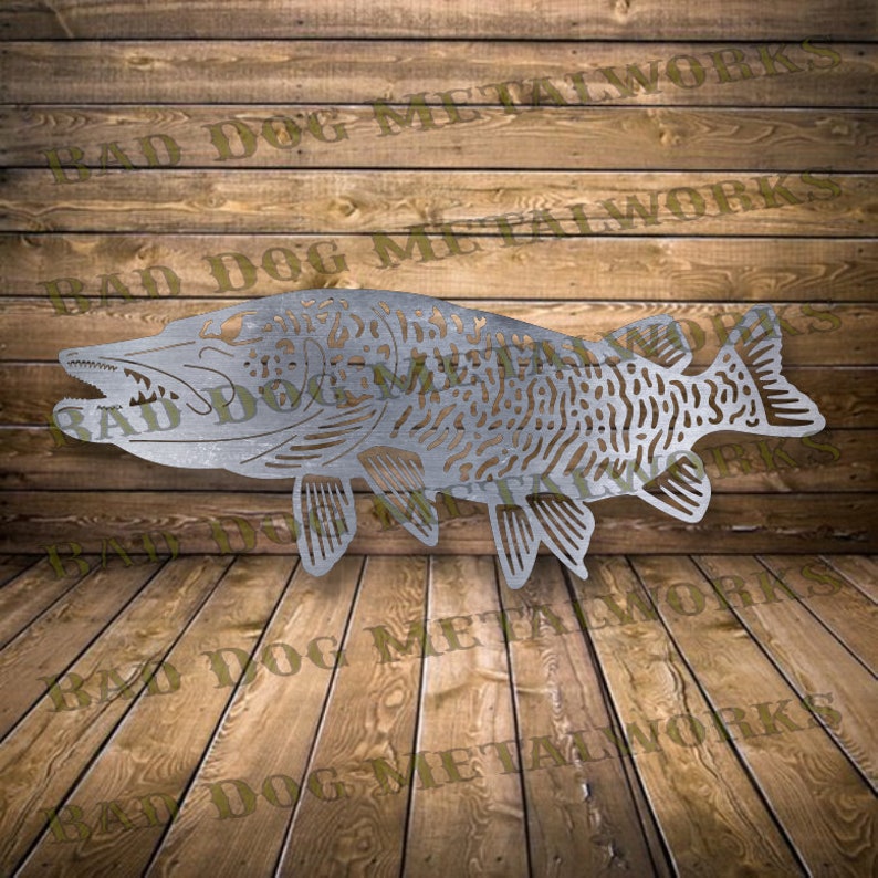 May include: A metal cutout of a silver-colored fish with a detailed design. The fish is facing left and has a long, thin body with fins and a tail. The fish is on a wooden background.