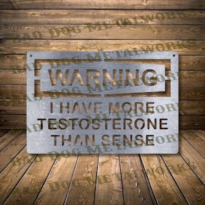 Puede incluir: Un letrero de metal plateado con el texto "WARNING I HAVE MORE TESTOSTERONE THAN SENSE" sobre un fondo de madera.