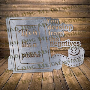 Puede incluir: Arte de pared de metal con un marco de imagen con el texto "Life is like a picture" y un carrete de película con el texto "You develop from the negatives".