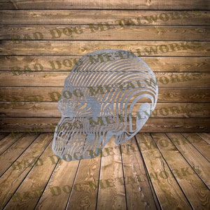 Könnte beinhalten: Eine Metallskulptur eines Schädels mit einem geschichteten, gestreiften Design. Der Schädel ist nach rechts gerichtet und aus silberfarbenem Metall gefertigt.