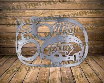 May include: Metal wall art featuring handcuffs, a whip, and a collar with the text "Let's Play".