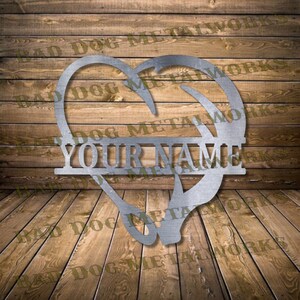May include: Metal heart-shaped silhouette with a deer antler design and a personalized nameplate that reads "YOUR NAME". The silhouette is made of brushed metal and has a rustic, industrial look.