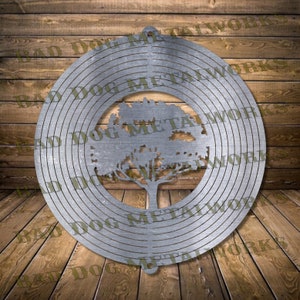 Puede incluir: Un molinillo de viento de metal con un diseño de árbol en el centro. El molinillo tiene círculos concéntricos con un acabado de metal cepillado. El árbol está silueteado contra el metal.