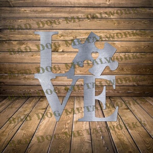 May include: Metal wall art sculpture of the word "LOVE" with a puzzle piece replacing the "O". The puzzle piece has a heart in the center. The sculpture is made of silver metal and has a rustic, distressed look.