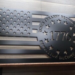 May include: Black metal American flag wall art with a circle cutout featuring the text "When Tyranny Becomes Law, Rebellion Becomes Duty" and the year "1776".