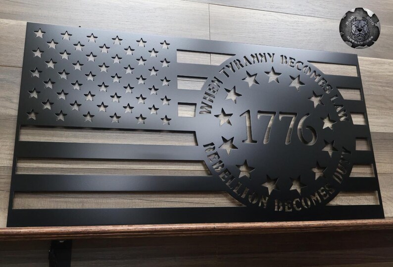May include: Black metal American flag wall art with a circle cutout featuring the text "When Tyranny Becomes Law, Rebellion Becomes Duty" and the year "1776".
