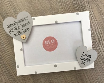 May include: White picture frame with gray polka dots and two gray wooden hearts. The top heart has the text "Grandparents fill the world with love" and a small beige button. The bottom heart has the text "Love Amelia x".