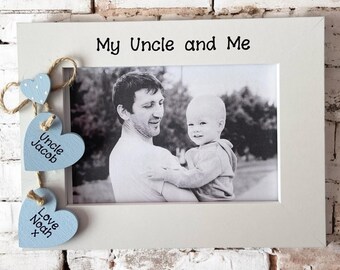 May include: White photo frame with a black and white photo of an uncle and nephew. The frame has blue wooden hearts hanging from it with the text "My Uncle and Me", "Uncle Jacob" and "Love Noah" on them.