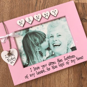 May include: A pink photo frame with the word "Nanny" spelled out in heart-shaped letters. The frame contains a black and white photo of a woman and a child. A heart-shaped tag says "Love Ruby x". The text "I love you from the bottom of my heart...to the tips of my toes" is written on the frame.