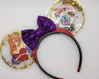 May include: Purple sequin bow headband with clear plastic ears featuring a cartoon image of Roger Rabbit and Jessica Rabbit with gold glitter inside.