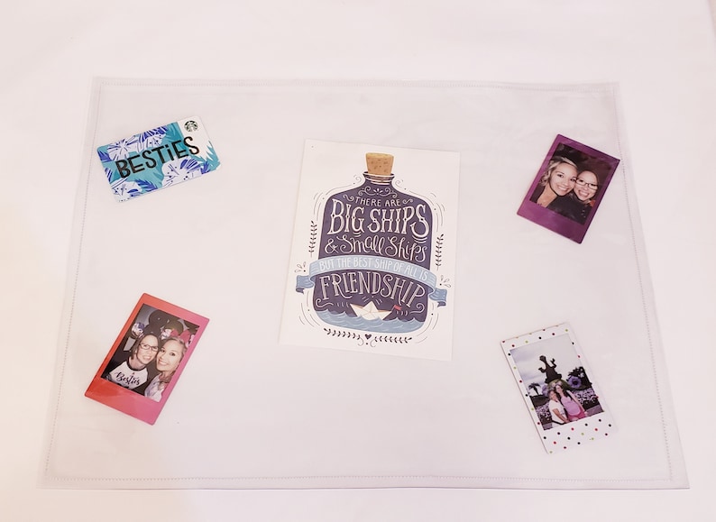 May include: A white card with a blue and purple bottle illustration and the text "There are big ships & small ships but the best ship of all is friendship". The card is surrounded by three Polaroid photos of two women and a photo of a building.