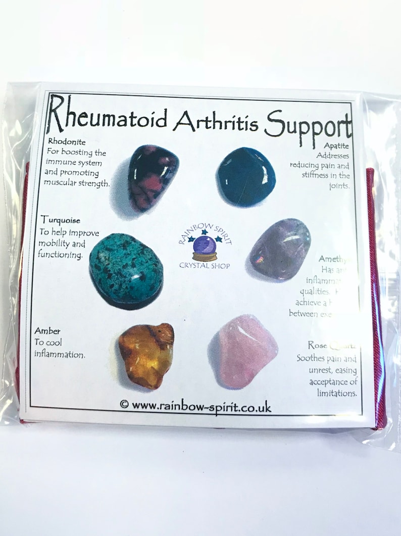 May include: A set of seven tumbled stones for rheumatoid arthritis support. The stones are rhodonite, turquoise, amber, amethyst, apatite, and rose quartz. The stones are arranged in a circle around a white card with the text "Rheumatoid Arthritis Support" and the name of each stone and its properties.