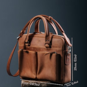 Peut inclure: Une mallette en cuir marron avec une longue sangle et deux poches avant. Le sac mesure 37 cm de large, 18 cm de profondeur et 28 cm de haut.