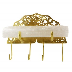 Op de afbeelding: Gouden metalen sleutelhanger met een stervormig ontwerp en een plank van selenietkristal. De sleutelhanger heeft vier haken.
