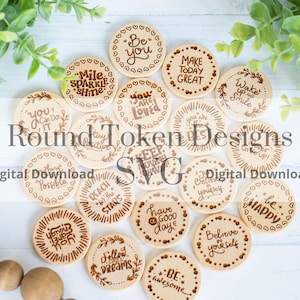 May include: A selection of round wooden tokens, each engraved with motivational phrases like "Believe in Yourself" and "Have a Good Day". The tokens are arranged on a white surface and feature dark brown text and decorative borders.