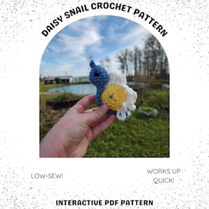 May include: A crochet pattern for a daisy snail amigurumi. The snail is blue with a yellow daisy shell and white petals. The pattern is described as low-sew and quick to work up. The image includes the text "Daisy Snail Crochet Pattern", "Low-Sew!" and "Works Up Quick!" and "Interactive PDF Pattern".