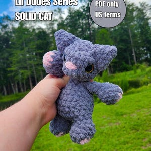 Op de afbeelding: Een grijs gehaakt kattenknuffeltje uit de Lil Dudes Series, met zacht textuurgaren, roze pootkussentjes en donkere ogen. De afbeelding bevat de tekst Lil Dudes Series, SOLID CAT en PDF only US terms in een grijze cirkel.
