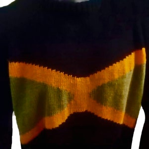 Puede incluir: Un suéter de punto negro con un diseño de lazo amarillo y verde.