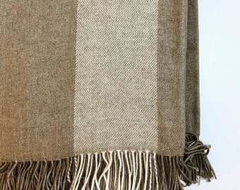 Könnte beinhalten: Eine braune und beige gestreifte Wolldecke mit Fransenrand.