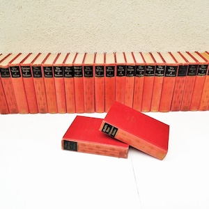 Pu&ograve; includere: Un set di 28 libri in brossura rossa con lettere dorate. I libri sono disposti in fila e sono tutti della stessa dimensione. I titoli dei libri sono "The Works of Shakespeare", "The Works of Dickens", "The Works of Scott", "The Works of Austen", "The Works of Browning", "The Works of Carlyle", "The Works of Coleridge", "The Works of De Quincey", "The Works of Emerson", "The Works of Fielding", "The Works of Goldsmith", "The Works of Hawthorne", "The Works of Irving", "The Works of Keats", "The Works of Lamb", "The Works of Macaulay", "The Works of Milton", "The Works of Pope", "The Works of Ruskin", "The Works of Shelley", "The Works of Spenser", "The Works of Swift", "The Works of Tennyson", "The Works of Thackeray", "The Works of Wordsworth" e "The Works of Chaucer".