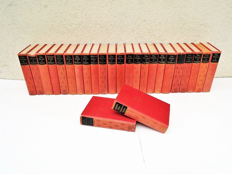 Pu&ograve; includere: Un set di 28 libri in brossura rossa con lettere dorate. I libri sono disposti in fila e sono tutti della stessa dimensione. I titoli dei libri sono "The Works of Shakespeare", "The Works of Dickens", "The Works of Scott", "The Works of Austen", "The Works of Browning", "The Works of Carlyle", "The Works of Coleridge", "The Works of De Quincey", "The Works of Emerson", "The Works of Fielding", "The Works of Goldsmith", "The Works of Hawthorne", "The Works of Irving", "The Works of Keats", "The Works of Lamb", "The Works of Macaulay", "The Works of Milton", "The Works of Pope", "The Works of Ruskin", "The Works of Shelley", "The Works of Spenser", "The Works of Swift", "The Works of Tennyson", "The Works of Thackeray", "The Works of Wordsworth" e "The Works of Chaucer".
