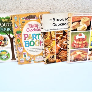 May include: Three vintage Betty Crocker cookbooks with colorful covers. The first book is titled "Betty Crocker's Outdoor Cookbook" and features a green tree and a red cabin. The second book is titled "Betty Crocker's Party Book" and features a yellow cover with a party hat, a cake, and a bunny. The third book is titled "The Bisquick Cookbook" and features a yellow cover with a variety of baked goods, including biscuits, waffles, and pancakes.
