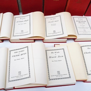 Pu&ograve; includere: Una collezione di libri in brossura rossa con titoli bianchi. I titoli includono "The Works of Charles Dickens", "The Works of A. Conan Doyle", "The Works of Alexandre Dumas", "The Works of Ralph Waldo Emerson", "The Works of Victor Hugo", "The Works of Henrik Ibsen" e "The Works of Charles & Mary Lamb".