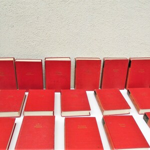 Pu&ograve; includere: Una collezione di 24 libri in brossura rigida rossa con scritte dorate sui dorsi. I libri sono disposti in tre file di otto libri ciascuna.