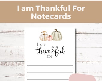 May include: Printable digital download of a Thanksgiving themed notecard with a white background and three white pumpkins with pink accents. The notecard says "I am thankful for" with lines for writing.