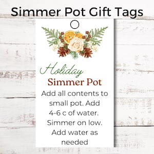 Pode incluir: Etiqueta de presente branca com um design floral verde, marrom e laranja. A etiqueta tem um furo no topo para uma corda. O texto na etiqueta diz "Holiday Simmer Pot" e inclui instruções para usar a panela de cozimento lento: "Adicione todo o conteúdo a uma panela pequena. Adicione 4-6 xícaras de água. Cozinhe em fogo baixo. Adicione água conforme necessário."