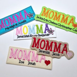 May include: Five colorful embroidered patches with the word "MOMMA" in different colors and fonts. Each patch has a small heart or flower design and a personalized name or names below the word "MOMMA".