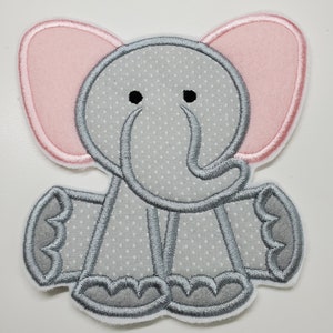 May include: A gray and pink felt elephant applique with a dotted pattern. The elephant has large pink ears, a gray trunk, and gray feet.