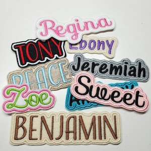 May include: A collection of embroidered name patches in various colors and fonts. Names include "Regina", "Tony", "Ebony", "Jeremiah", "Sweet", "Peace", "Zoe", and "Benjamin". Each patch has a unique design and color scheme.