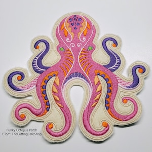 Peut inclure: Un patch brodé d'une pieuvre rose et violette avec des détails complexes. La pieuvre a un fond blanc et est entourée d'une bordure blanche.