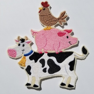 May include: An embroidered patch featuring a cow, pig, and chicken. The cow is white with black spots and has a blue collar with a yellow bell. The pig is pink and the chicken is brown with a red comb.