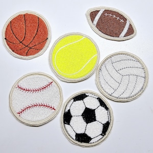 May include: Six embroidered patches featuring different sports balls: a basketball, a tennis ball, a volleyball, a baseball, a soccer ball, and a football. The patches are all white with a cream-coloured border.