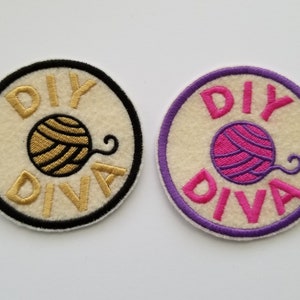May include: Two round patches with the text "DIY DIVA" and a yarn ball design. One patch has gold text and a black border, the other has pink text and a purple border. Both patches have a cream-colored background.