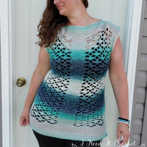 May include: A crocheted top with a blue, green and white colour gradient. The top has a loose fit and a wide neckline. The top is made with a lacy stitch pattern.