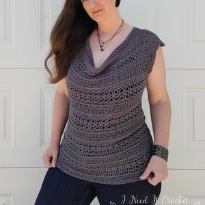 May include: A gray crochet top with a cowl neck and short sleeves. The top is made with a lacy stitch pattern and has a relaxed fit.