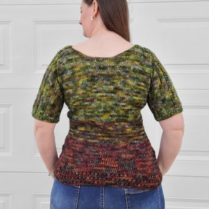 May include: A green, brown, and orange crochet top with a scoop neck and short sleeves. The top has a fitted bodice and a flared hem.