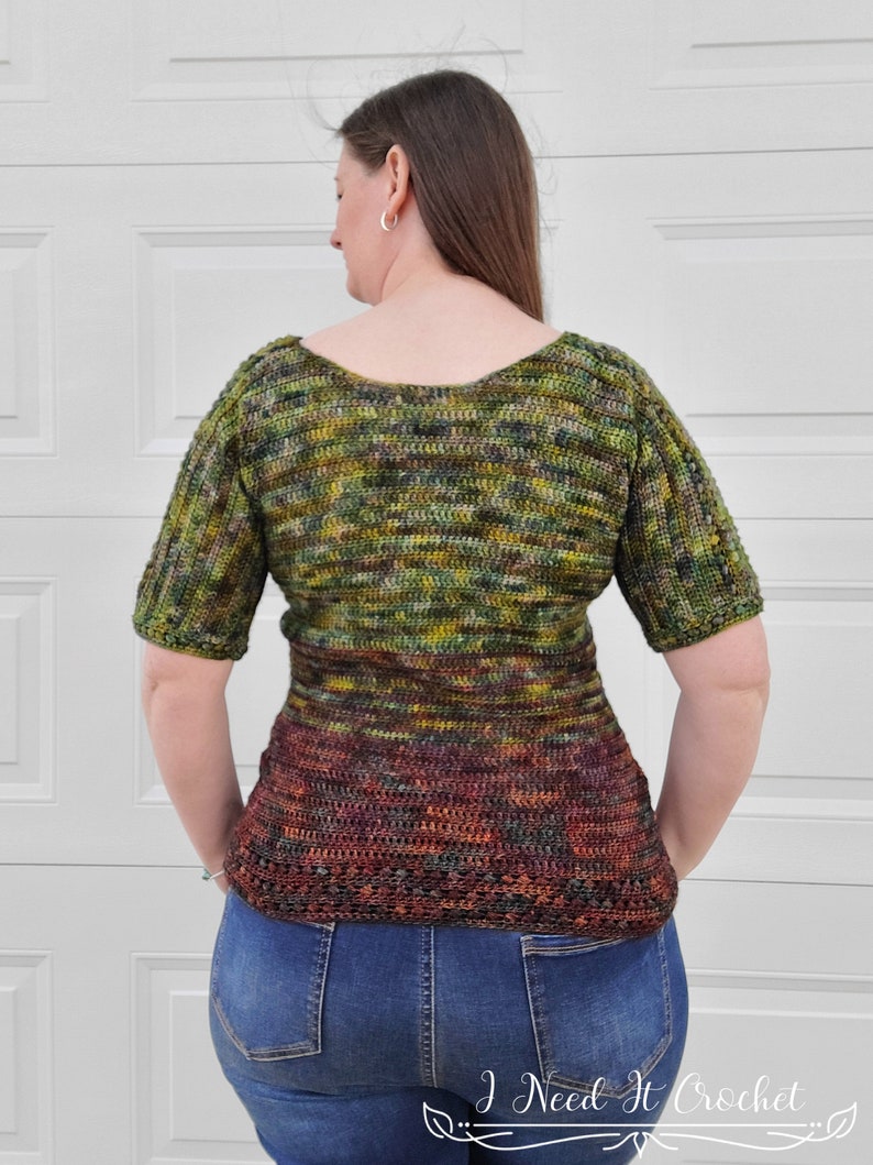 May include: A green, brown, and orange crochet top with a scoop neck and short sleeves. The top has a fitted bodice and a flared hem.