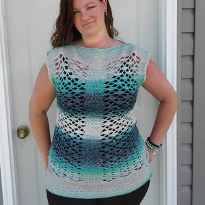 May include: A crocheted top with a blue, green and white ombre pattern. The top has a wide, open neckline and short sleeves. The top is made with a lacy stitch and has a loose, flowy fit.