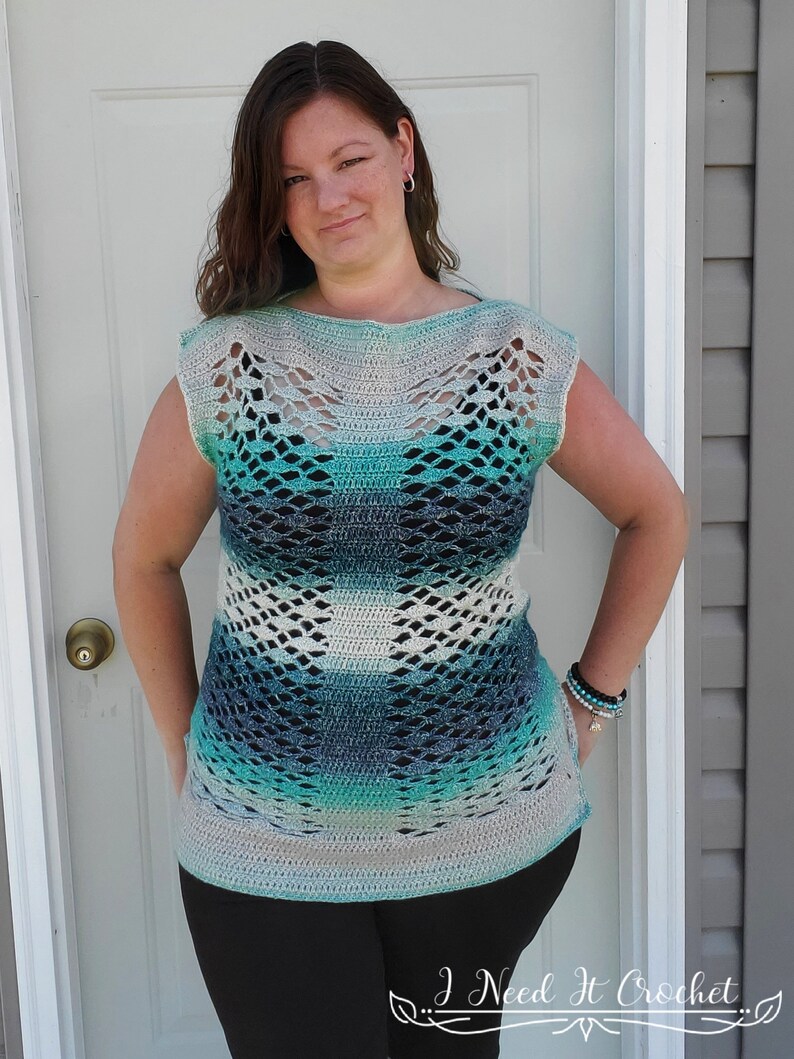 May include: A crocheted top with a blue, green and white ombre pattern. The top has a wide, open neckline and short sleeves. The top is made with a lacy stitch and has a loose, flowy fit.