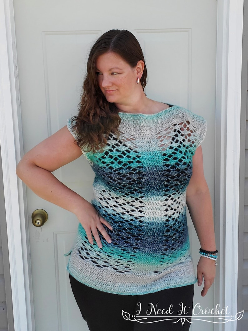 May include: A crocheted top with a blue, green and white ombre pattern. The top has a loose fit and a wide neckline. It features a delicate openwork design throughout.